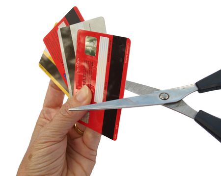 3546618 - four credit cards held in a hand, being cut up with pair of scissors.